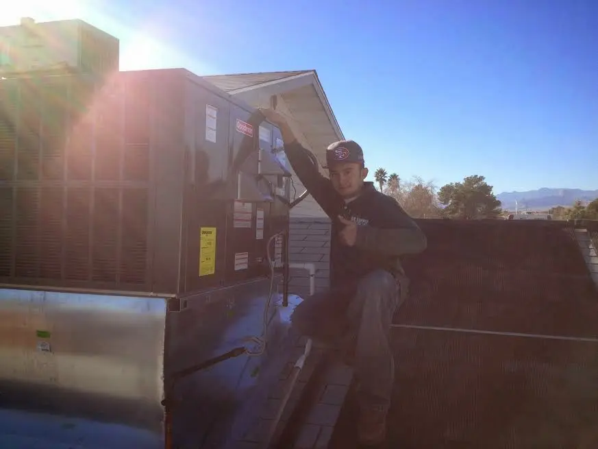 HVAC technician performing Air Duct Cleaning on a rooftop unit in Sappington